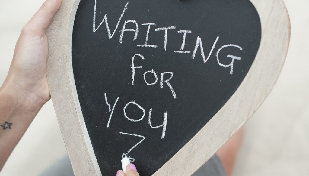 A pregnant woman holds a sign for her unborn baby that says "waiting for you"